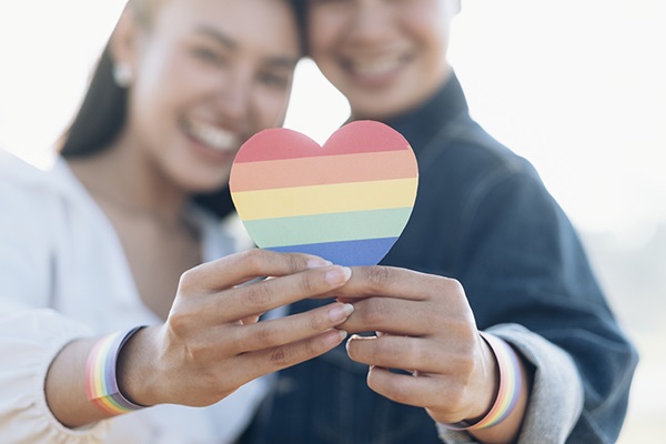 Two people holding a rainbow heart in focus